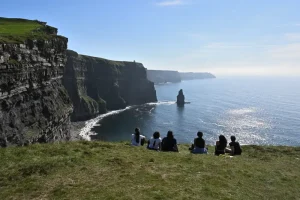 A group of visitors sitting and enjoying the scenery at the Cliffs of Moher